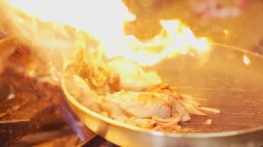 Frying pan in flames. Professional chef cooking ingredients for shrimp pasta with the use of fire. Restaurant kitchen. High quality 4k footage