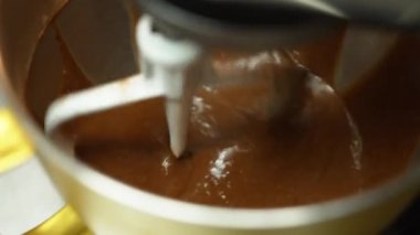 Close-up shot of stand mixer mixing chocolate cupcake butter in golden bowl. Professional baking process. Kitchen appliences. Horizontal indoor shot. High quality 4k footage