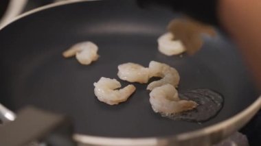 Small shrimps on a frying pan. Preparation of a restaurant dish. Seafood and eating out concept. High quality 4k footage