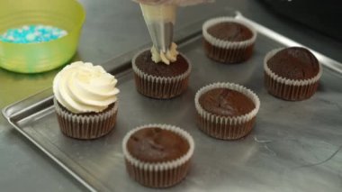 adding whipped cream to the chocolate cupcakes, bakery, dessert concept. High quality 4k footage