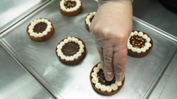 ベーカリーのチョコレートケーキに黄金のスプリンクルを追加するパン屋の手のクローズアップビュー 高品質4K映像 — ストック動画