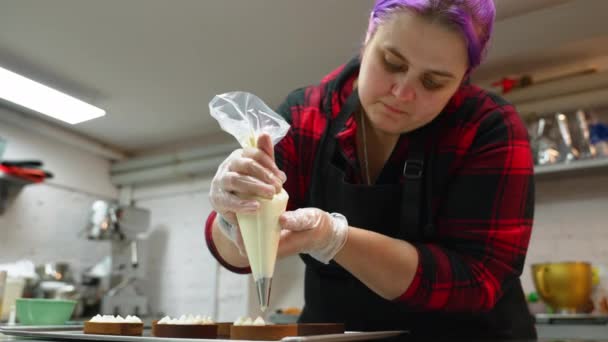 一人のビジネスコンセプト バニラバタークリームのフリストでチョコレートタルトを飾るためにペストリーバッグを使用した才能あるパン屋 屋内で撃たれた 高品質4K映像 — ストック動画