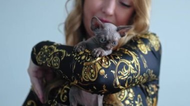 Woman hugging Devon Rex kitten with both hands. High quality 4k footage