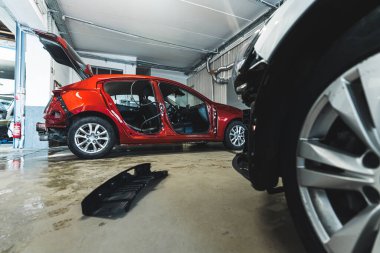 An auto body repair shop with luxury cars in various stages of collision repair. High-quality photo