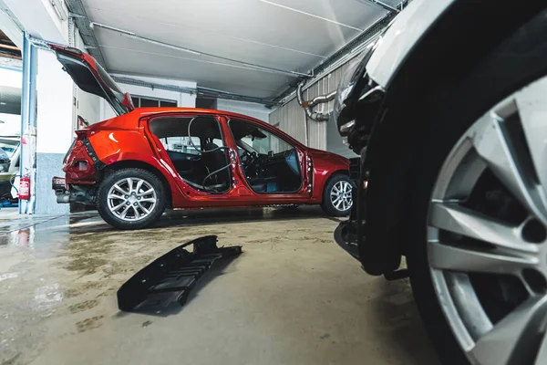 An auto body repair shop with luxury cars in various stages of collision repair. High-quality photo