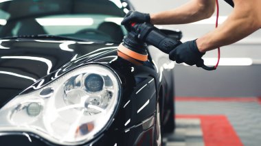 Headlight detail of modern luxury car during detailing process - polishing the paintwork. Front view. Indoor shot. High quality photo