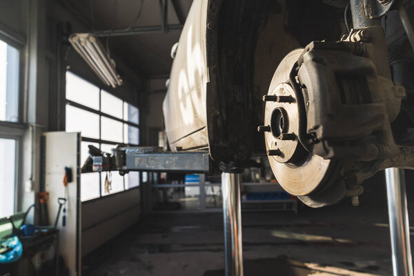 Close shot of a car brake disc with car repair shop in the background. High quality photo