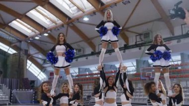 Low angle shot. Three groups of cheerleaders holding their teammates in the air. Extension stunt. Sport concept. High quality 4k footage