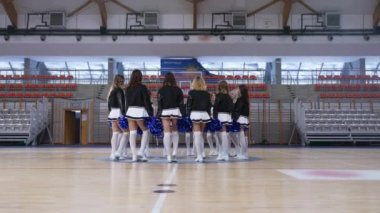 Full shot of blue pom-poms thrown up in the air by cheereladers gathered in a circle. Sport concept. High quality 4k footage