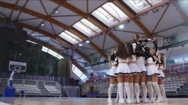 Full shot of a cheerlader being held by other cheerleaders and doing a full split. Sport concept. High quality 4k footage