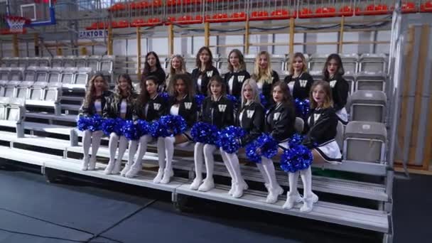 Group Cheerleaders Sitting White Bench Two Rows While Holding Blue — Stock Video