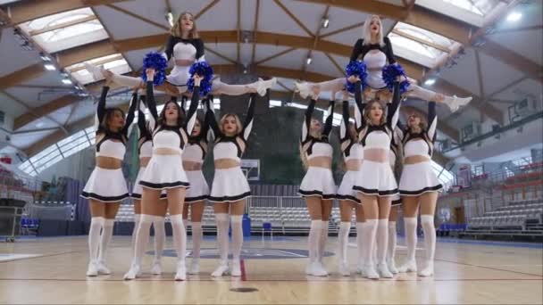 Cheerleaders Vibrant Pom Poms Executing Split Lift Stunt Indoor Court — Stockvideo