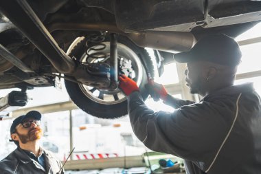 Close shot of two mechanics repairing a car wheel together. Repair shop concept. High quality photo