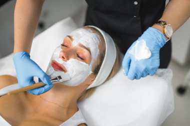 Beautiful White woman getting a white revitalising face beauty mask. High quality photo