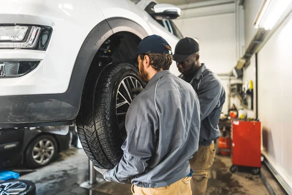 Car Mechanics Replacing Wheels Lifted Automobile Repair Service Station High — Stok fotoğraf