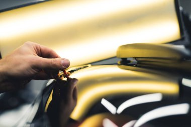 Bright lamp used during removal of small dents on a black car. Closeup shot of a mechanics hand during work. High quality photo