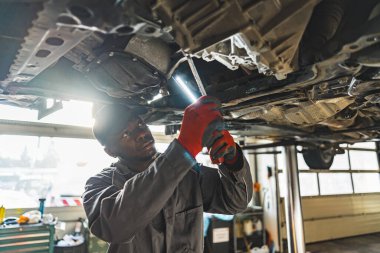 Skilled mechanic replacing a cars clutch using a torch in an auto repair shop. High-quality photo