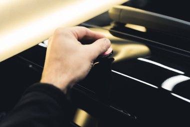 Car dent removal process. Man removing dents from body of car using bright lamp. Closeup indoor shot. Mechanics hand. Specialistic equipment. High quality photo