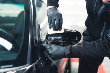 PPF wrapping process. Car side mirror being wrapped by protective film for car paint by a professional. Car detailing process. High quality photo