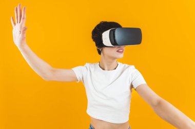 Excited girl getting experience using VR headset in studio over yellow background. Medium closeup shot. Virtual Reality concept. High quality photo