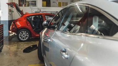 cars in auto repir shop, side view of a silver car and a red car in front of it. High quality photo