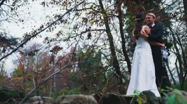 Newlyweds bride and groom embracing in a forest for their wedding photoshoot. High quality 4k footage