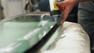 Skilled mechanic carefully adding glue to the windscreen of the car for replacement. High-quality 4k footage