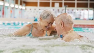 Romantic senior couple in a swimming pool embracing - Life after retirement. High-quality 4k footage