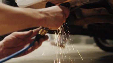 Skilled mechanic using a welding machine with intense sparks to repair the damaged body of a car. High-quality 4k footage