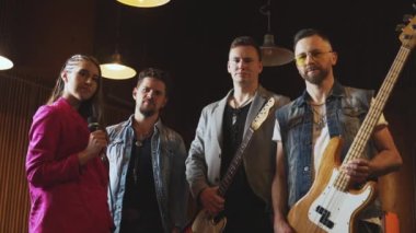 Bir kadın vokalist grubu, müzik grubu kayıt seansından sonra gitarist ve davulcuya sarılıyor. Yüksek kalite 4K görüntü