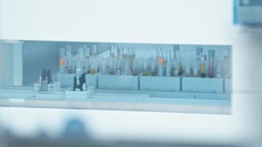 Long shot of automated test tube holders moving around behind the glass, with a lot of empty test tubes standing in the background. Lab concept. High quality 4k footage