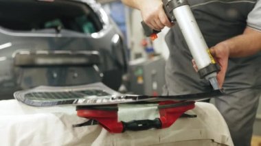 Worker applying an adhesive sealant to car windscreen preparing for replacement. High-quality 4k footage