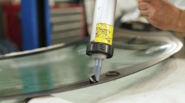 Worker applying an adhesive sealant to car windscreen preparing for replacement. High-quality 4k footage