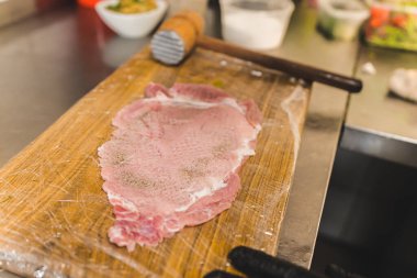 Piece of raw pork flattened down with a beater to make breaded cutlet schabowy. Polish cuisine. Restaurant kitchen preparation process. Horizontal indoor shot. High quality photo