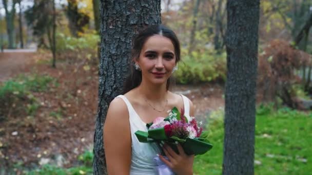 婚礼当天 漂亮的新娘身穿白色婚纱 手持鲜花在户外摆姿势 高质量的4K镜头 — 图库视频影像