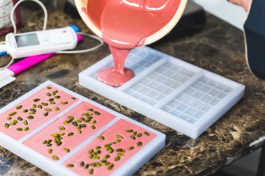 Craft pink chocolate being poured into a bar form, molding process. High quality photo