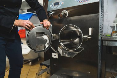 Man chef working with the ice cream maker machine in the small manufacturing. High quality photo