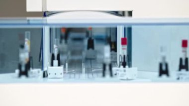 Inside of an automated lab glazed line. Two test tubes with red caps drawing away. Many empty test tubes moving in the foreground. Lap concept. High quality 4k footage