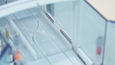 Test tubes in holders moving one after another in a line. Lab concept. Close shot. High quality 4k footage