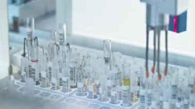 Close shot of a single test tube in a holder moving along the line of an automated lab. Lab concept. High quality 4k footage