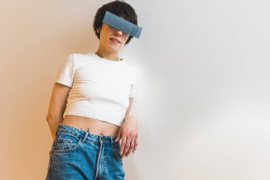 Stylish slim person wearing rectangular sunglasses and posing to the camera. White background. Medium indoor shot. High quality photo