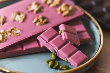 Closeup premium pink craft chocolate bars with whole nuts. High quality photo