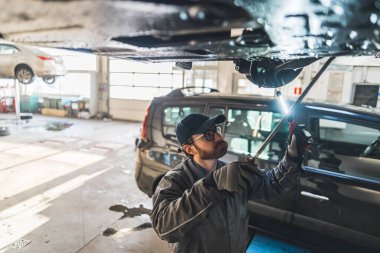 an auto mechanic making chassis inspection at a car workshop, medium shot. High quality photo