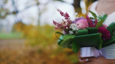 A bride holding a wedding bouquet of colourful flowers waiting for her groom. High quality 4k footage