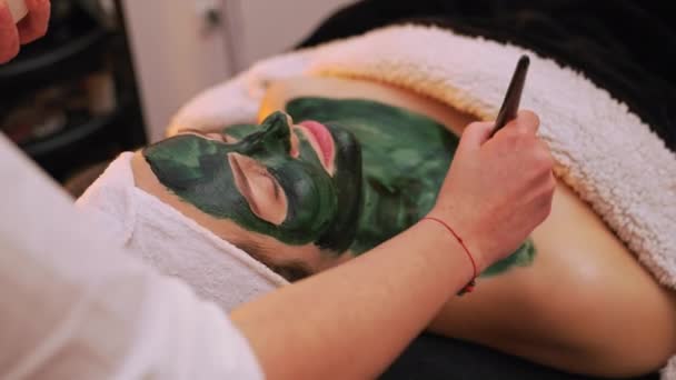 Side View Beautician Applying Green Face Mask Her Clients Cleavage — Stockvideo