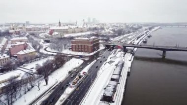 01.22.2023 - Warsaw, Poland. Aerial view of snowy city roads runnign by the river, with cars driving on it. Winter city concept. Vistula River. High quality 4k footage