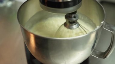Close up shot of food processor mixing pastry in a metal bowl. Blurred kitchen counter in the background. High quality 4k footage