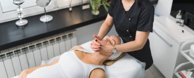 Pragnant Caucasian woman getting an face massage in beauty clinic. High quality photo