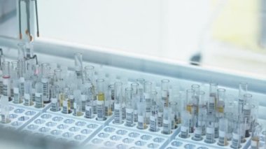 A robot hand picking up a test tube from one tray and putting it in another tray. Close shot. High quality 4k footage