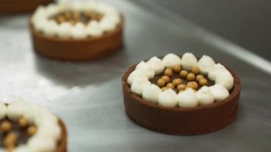 Close up shot of decorated tarts being sprayed with golden spray. Blurred tarts in the foreground and background. High quality 4k footage